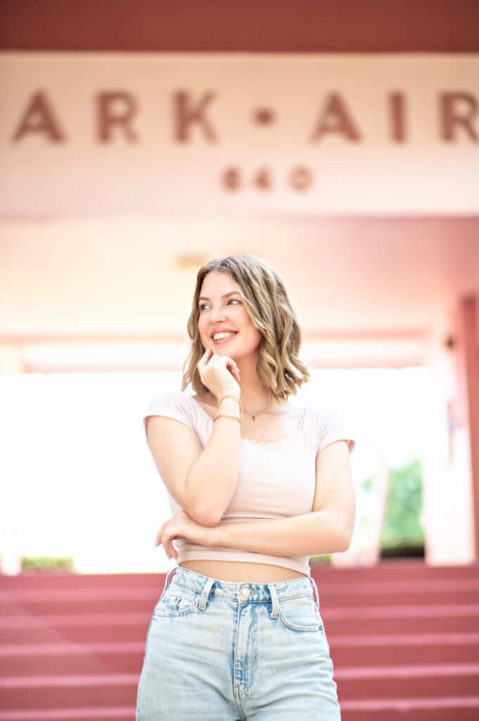 picture of a beautiful girl standing in front of a iconic pink apartment building in winter park