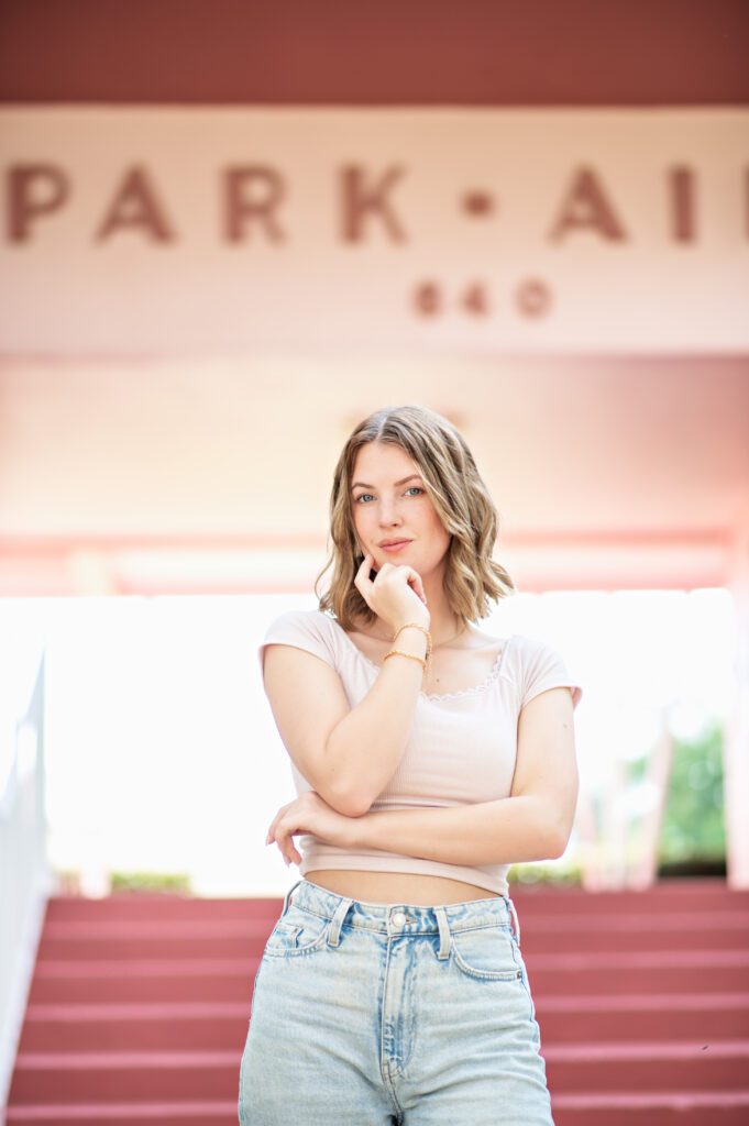 picture of a beautiful girl standing in front of a iconic pink apartment building in winter park