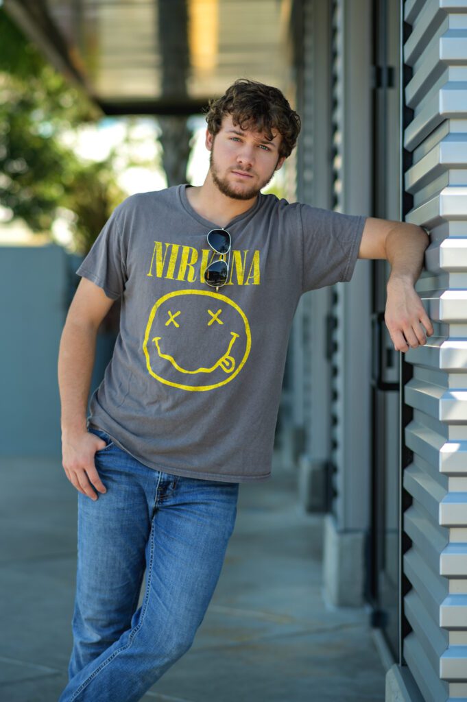 Orlando senior guy photography session at the glass house at Lake Nona, featuring a stylish high school senior posing confidently. Professional senior portraits for Class of 2025."