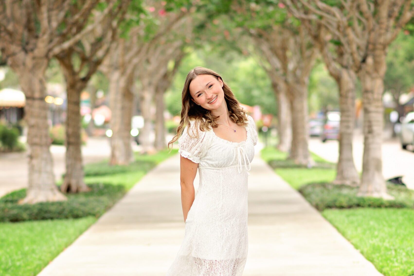 high school senior girl in white dress poses in downtown winter garden, fl