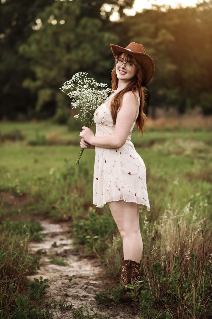 High school senior girl wearing cowgirl boots and wide-brim hat during golden hour in Orlando park