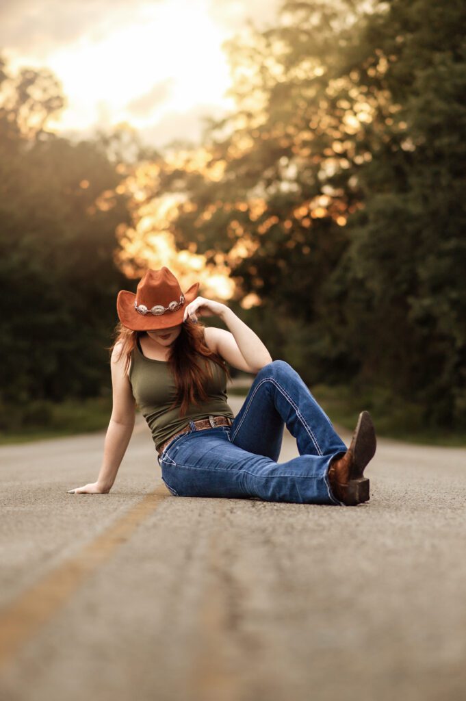 High school senior girl wearing cowgirl boots and wide-brim hat during golden hour in Orlando park