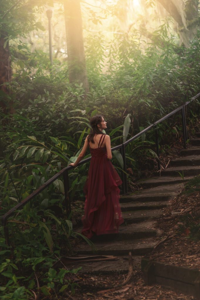 Senior walking up stone stairs with golden light illuminating the path, creating a fairytale-inspired photo