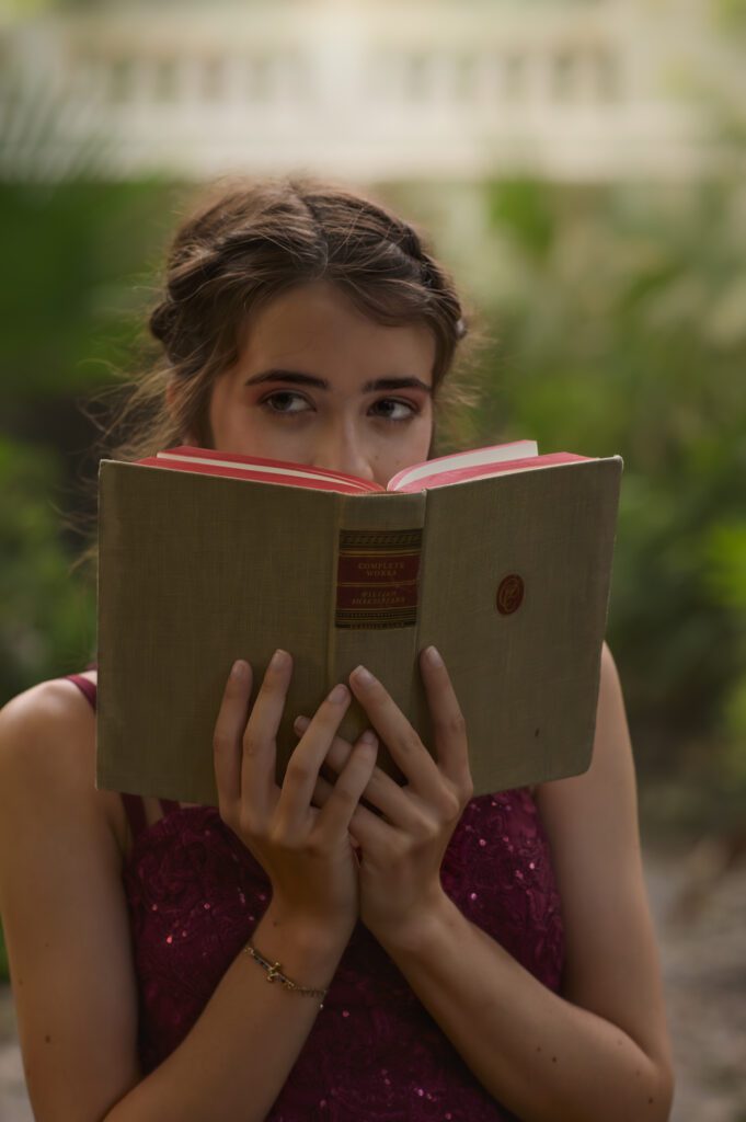 Whimsical portrait of a senior reading a hardcover book in a park in Orlando, Fl