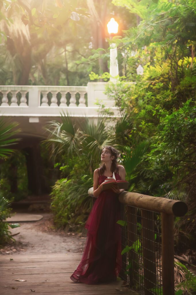 High school senior walking slowly through a hidden park, reading a book in soft natural light