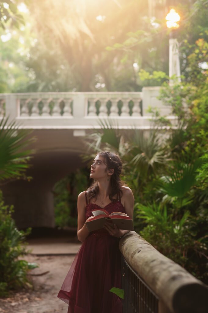 Dreamy photo of a senior looking up to the sky standing in a sun-dappled garden in Winter Park FL