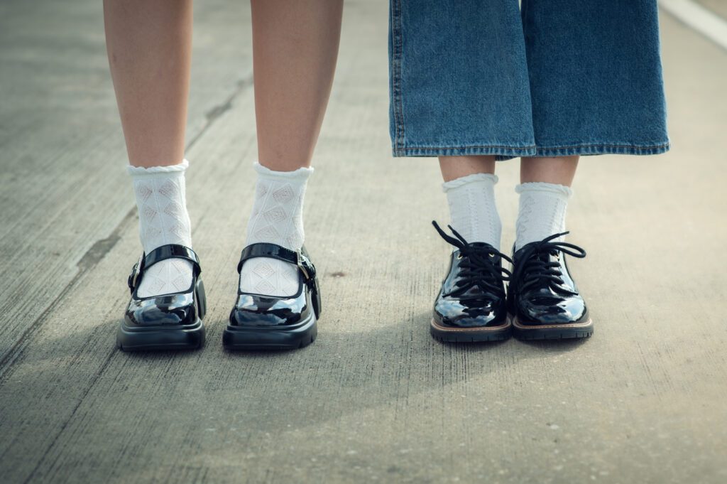 Detail shot of best friends’ sneakers and jeans with strong shadows across concrete in Winter Garden