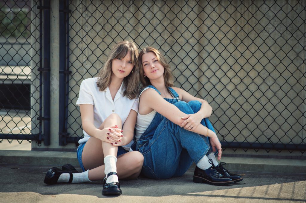 Moody close-up of two girls cheek to cheek, both wearing denim, with soft smiles