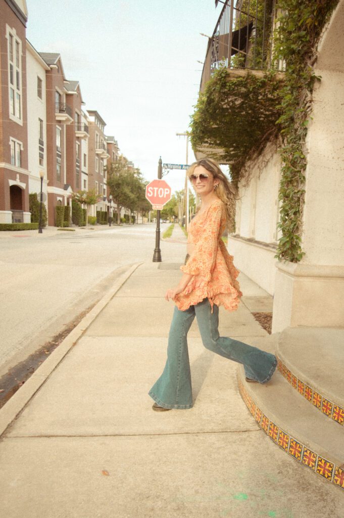 senior girl in bell bottom jeans and vintage top in downtown Winter Park during her 70's themed senior photo session.