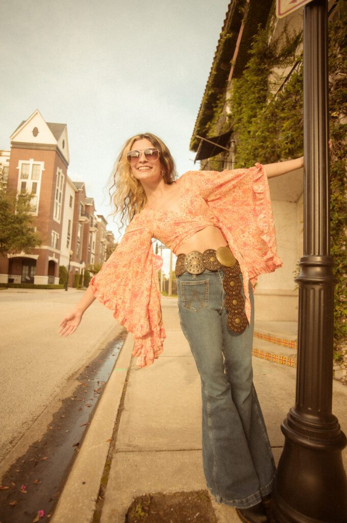senior girl in bell bottom jeans and vintage top in downtown Winter Park during her 70's themed senior photo session.