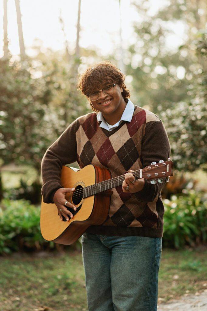 High school senior holding a guitar during a personalized senior photography session designed around their interests in Orlando.