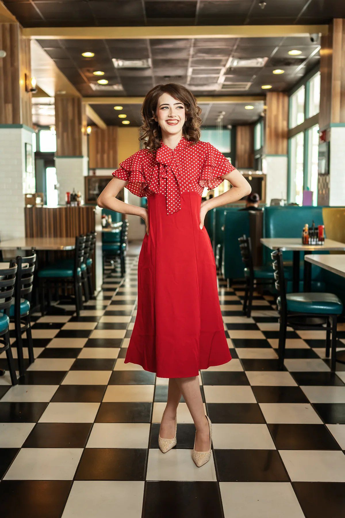 Creative senior portrait in a red polka-dot dress inside a retro diner near Orlando