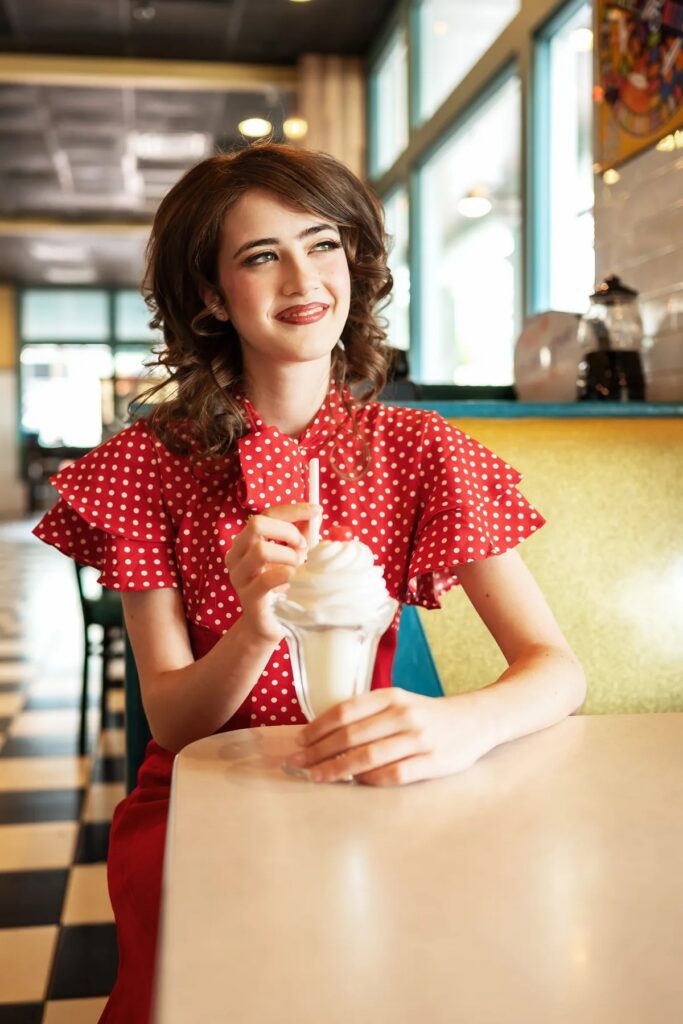 Playful senior portrait with a vintage telephone in a 1950s diner