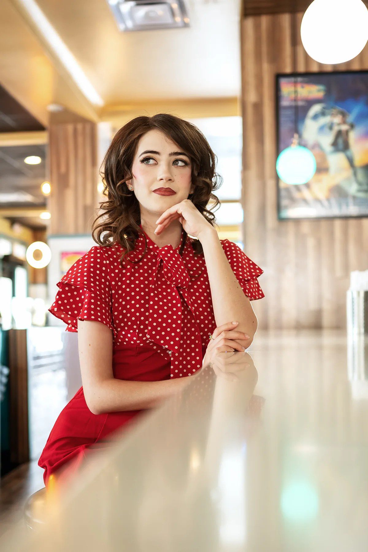 Smiling senior portrait in a vintage red dress inside a retro diner