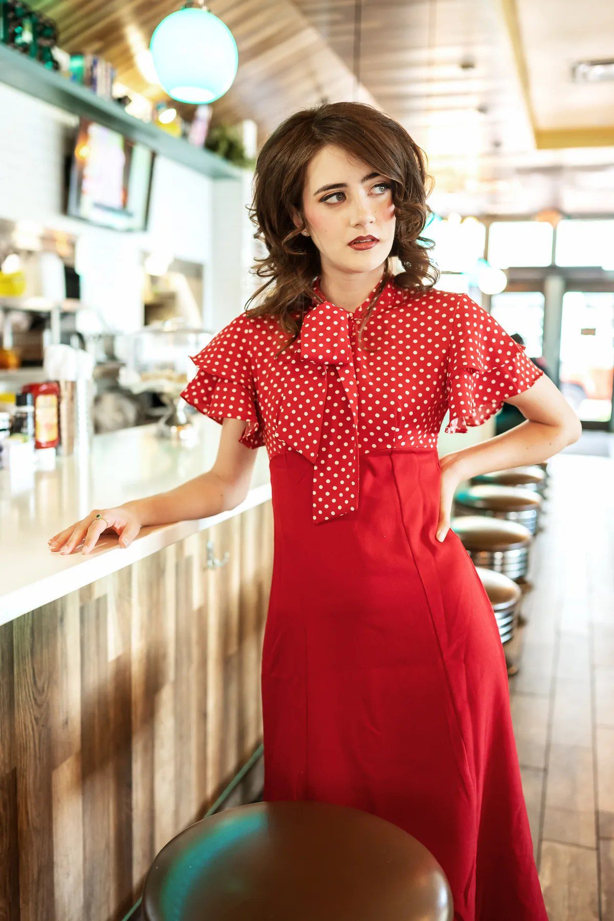 Senior portrait in a red polka-dot dress at a retro diner counter