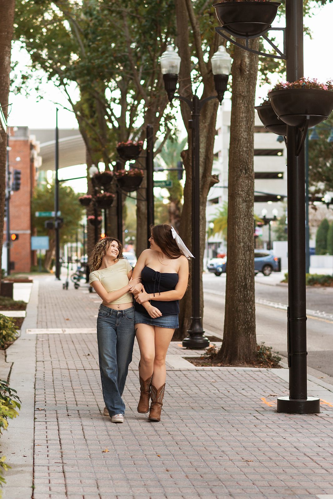 Two high school friends laughing as they walk along a Downtown Orlando sidewalk.