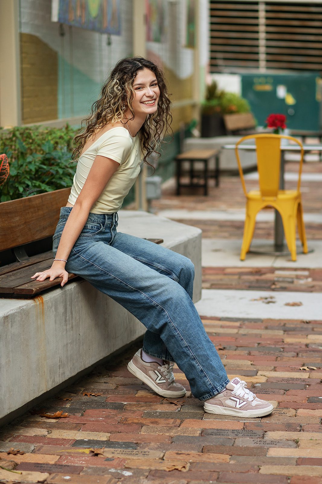 Senior girl laughing while seated near colorful café chairs in Downtown Orlando.