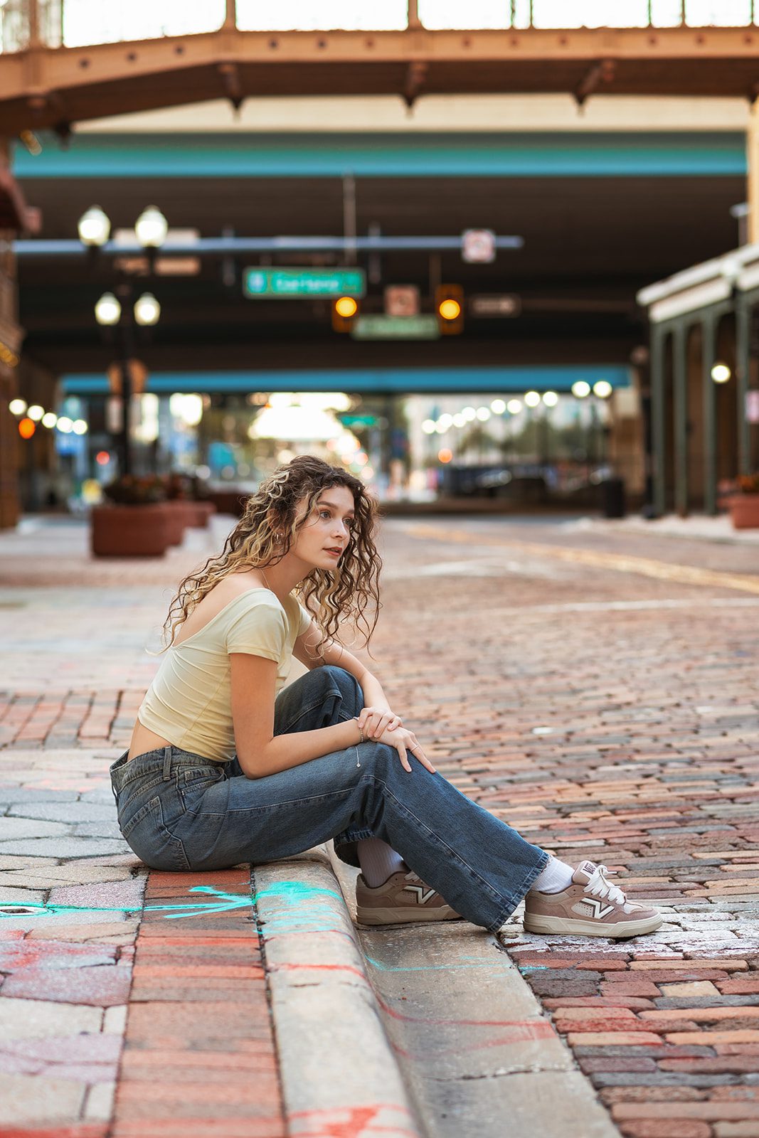 High school senior seated on the brick street beneath the Church Street Station overpass in Downtown Orlando.