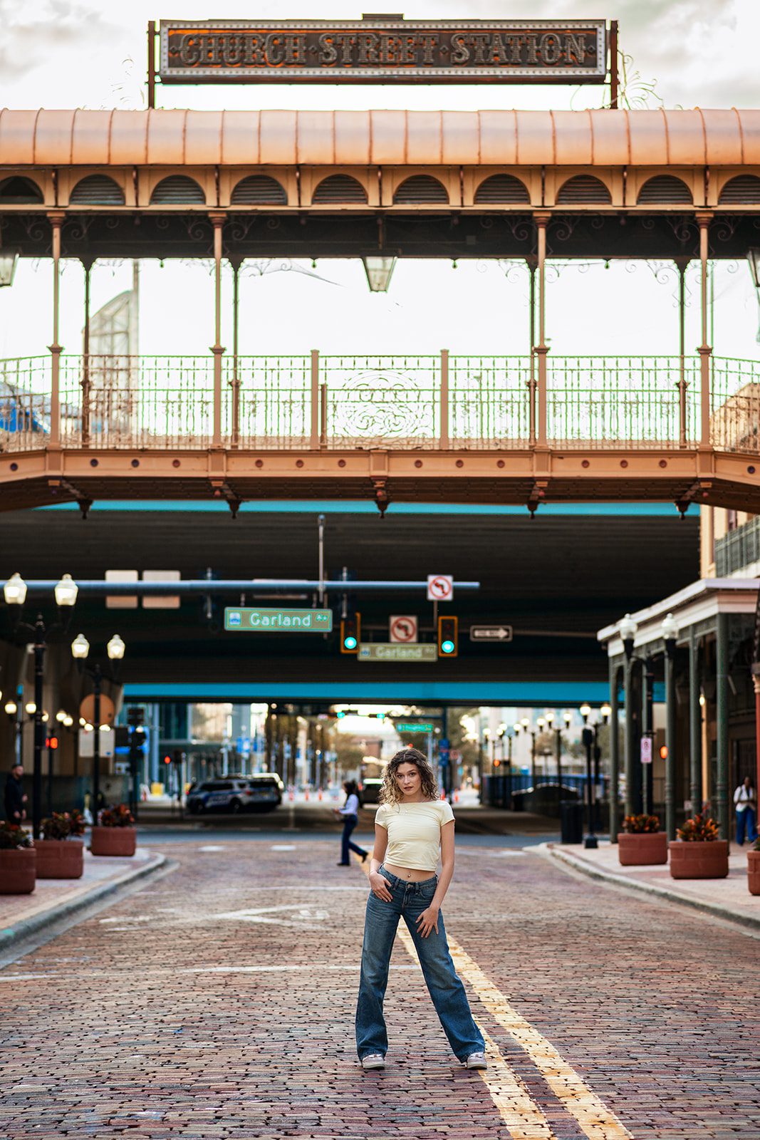 High school senior standing on the brick street beneath the Church Street Station sign in Downtown Orlando.