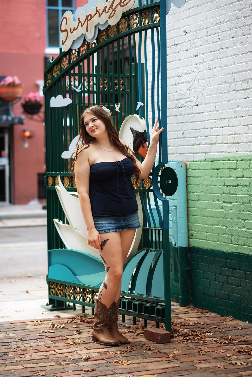 High school girl posing beside a colorful mural and metal gate in Downtown Orlando.