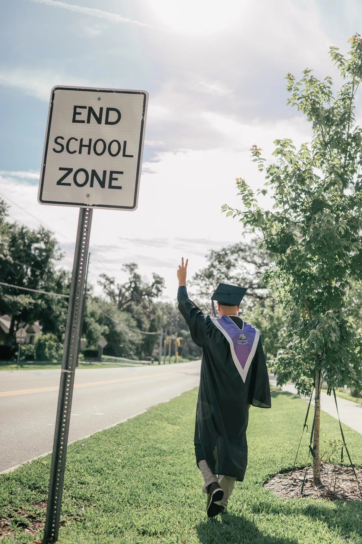 Graduation photo walking past an End School Zone sign
