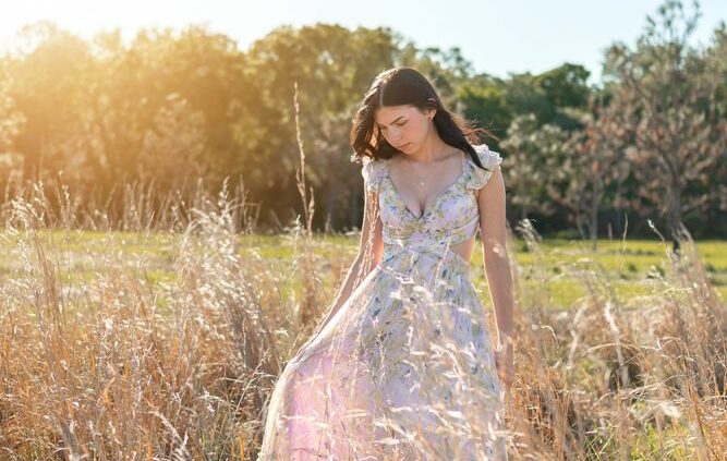 senior girl walking in field during senior pictures