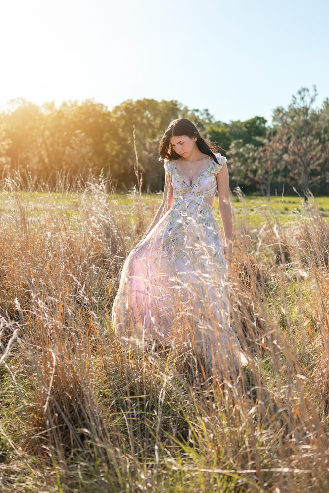 High school senior walking through a sunlit field during her Orlando senior pictures