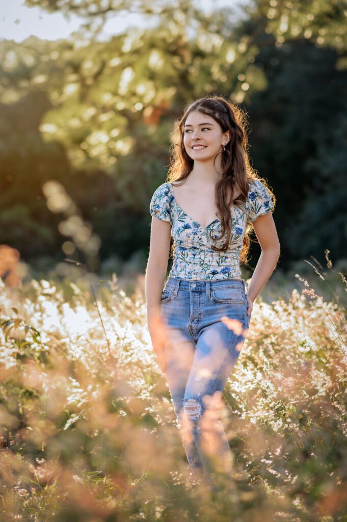 High school senior wearing a floral top and jeans during an outdoor senior photo session