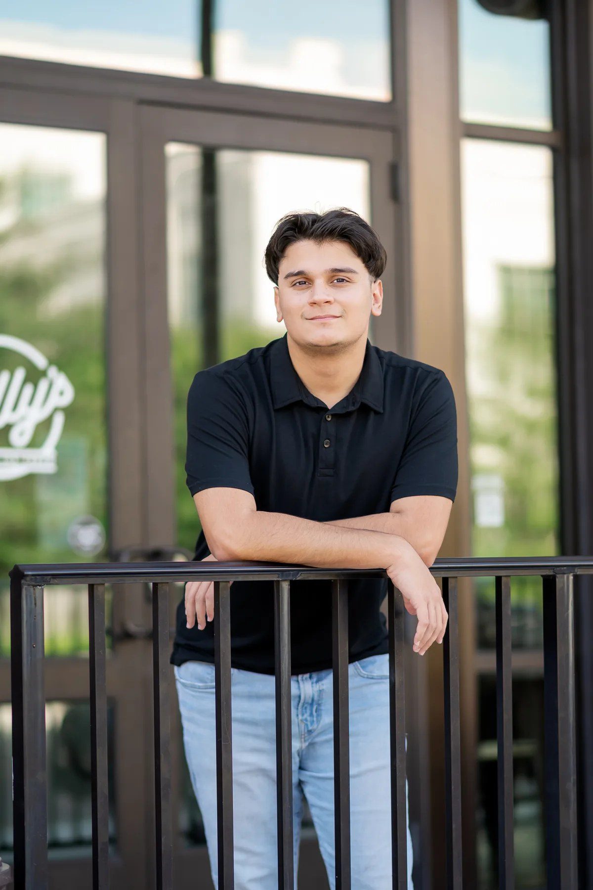 Casual senior portrait in a black shirt beside downtown architecture