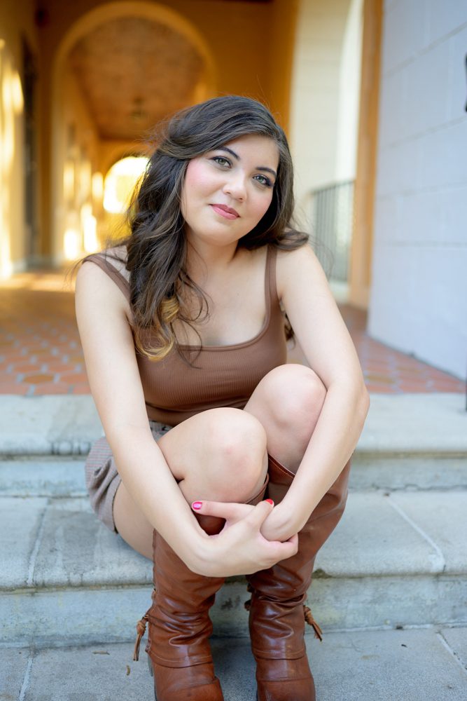 High school senior with softly styled hair and makeup posing outdoors