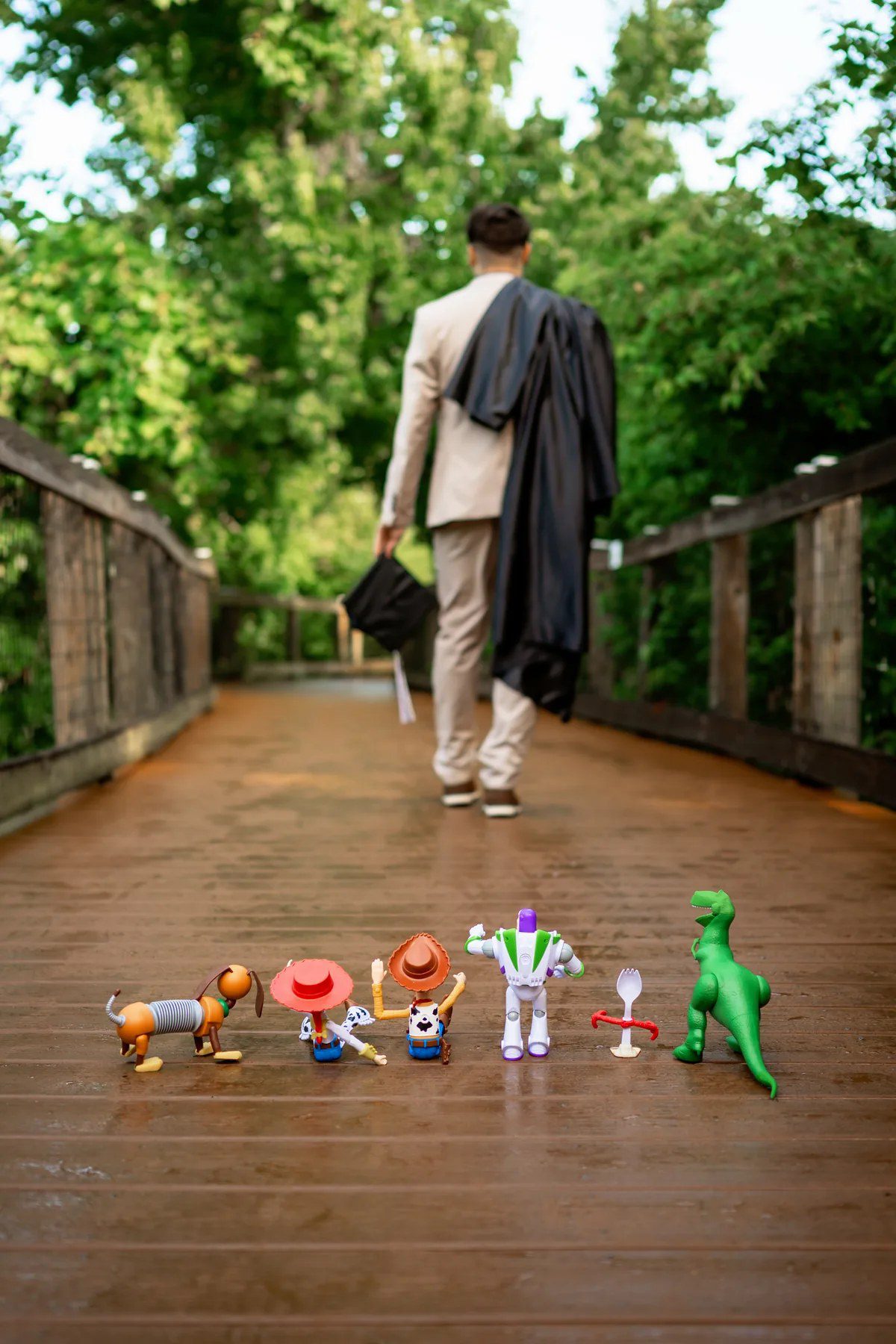Toy Story-inspired graduation picture with toys lined along the Oakland Nature Preserve boardwalk