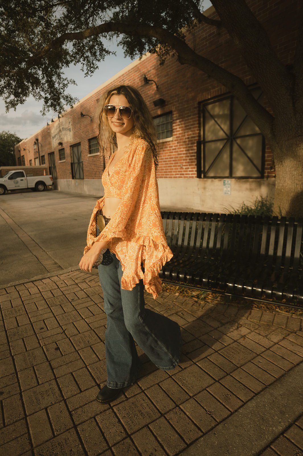 Keeleigh walking beside a brick building during her 1970s-inspired senior photo session in Winter Park.