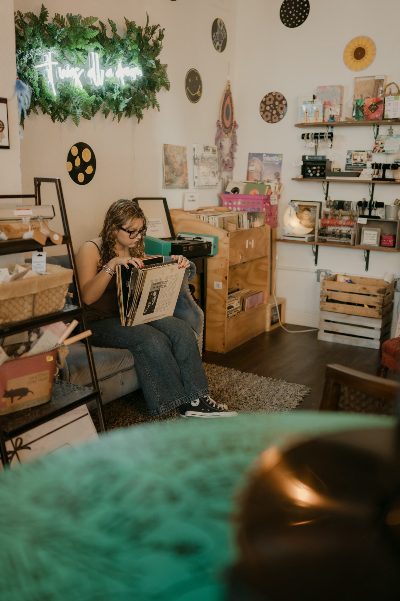 Senior in jeans posing beside colorful record displays in Clermont