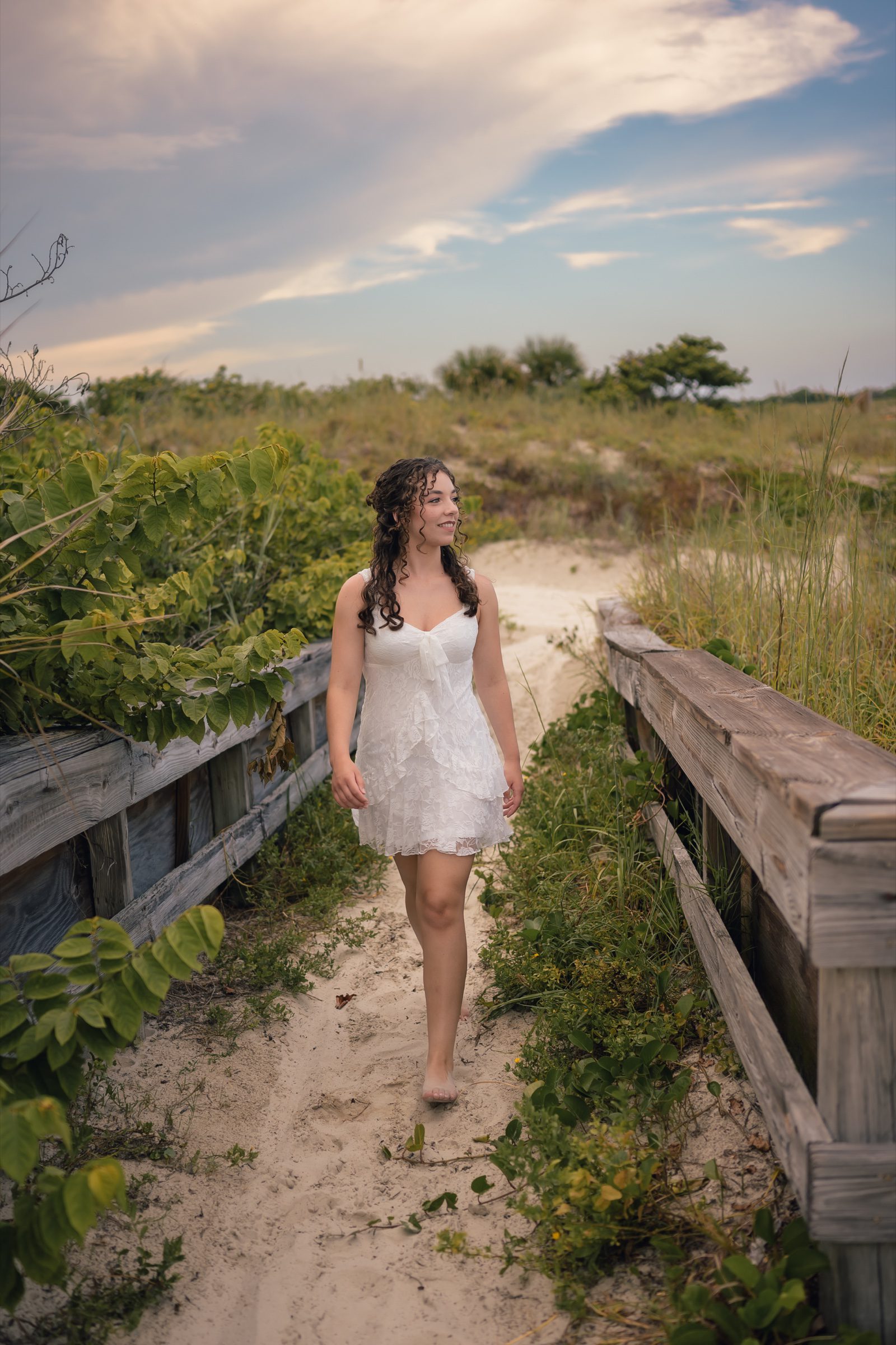Senior walking along a sandy beach path between wooden railings