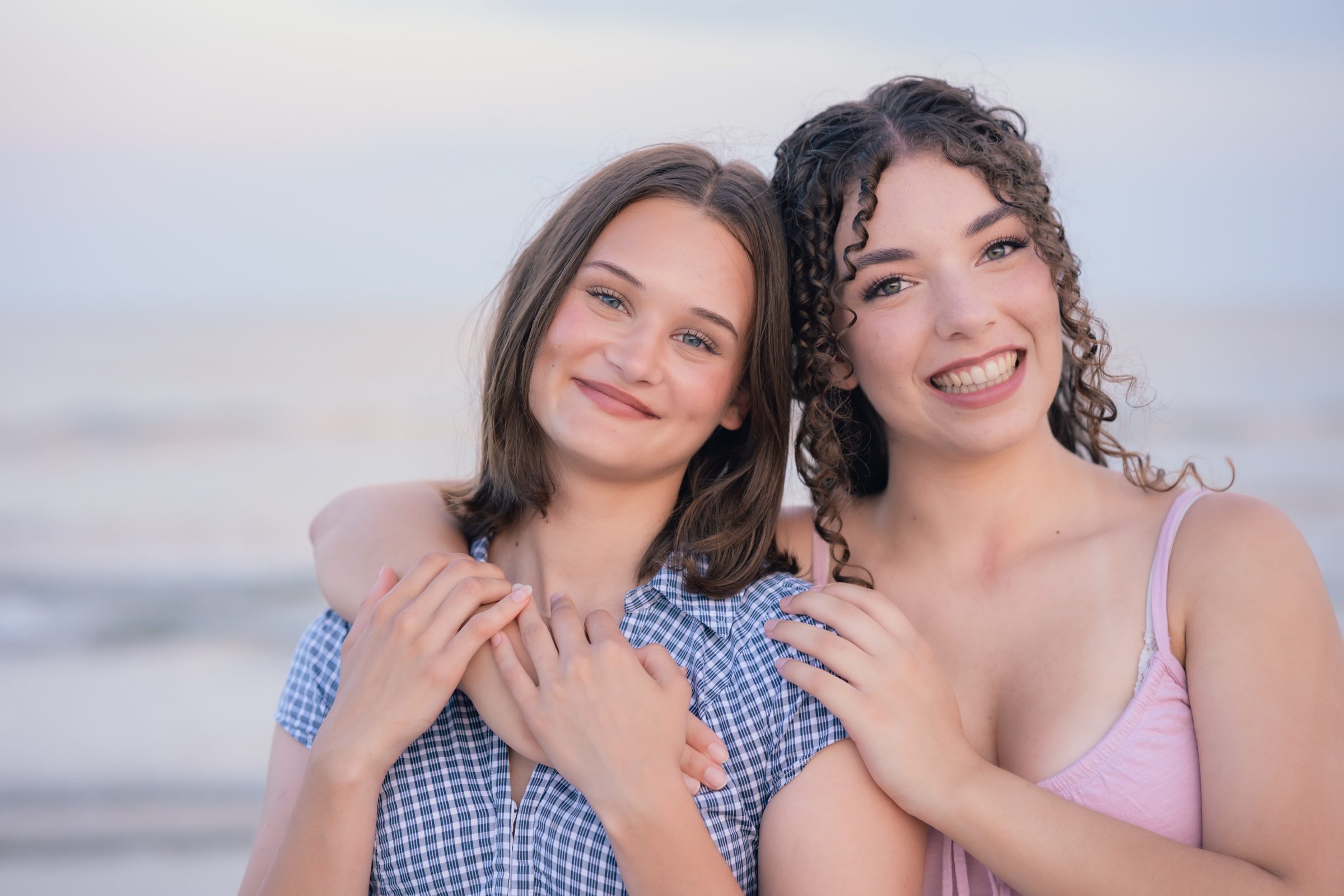 Senior and her best friend smiling during a beach photo session at Jetty Park