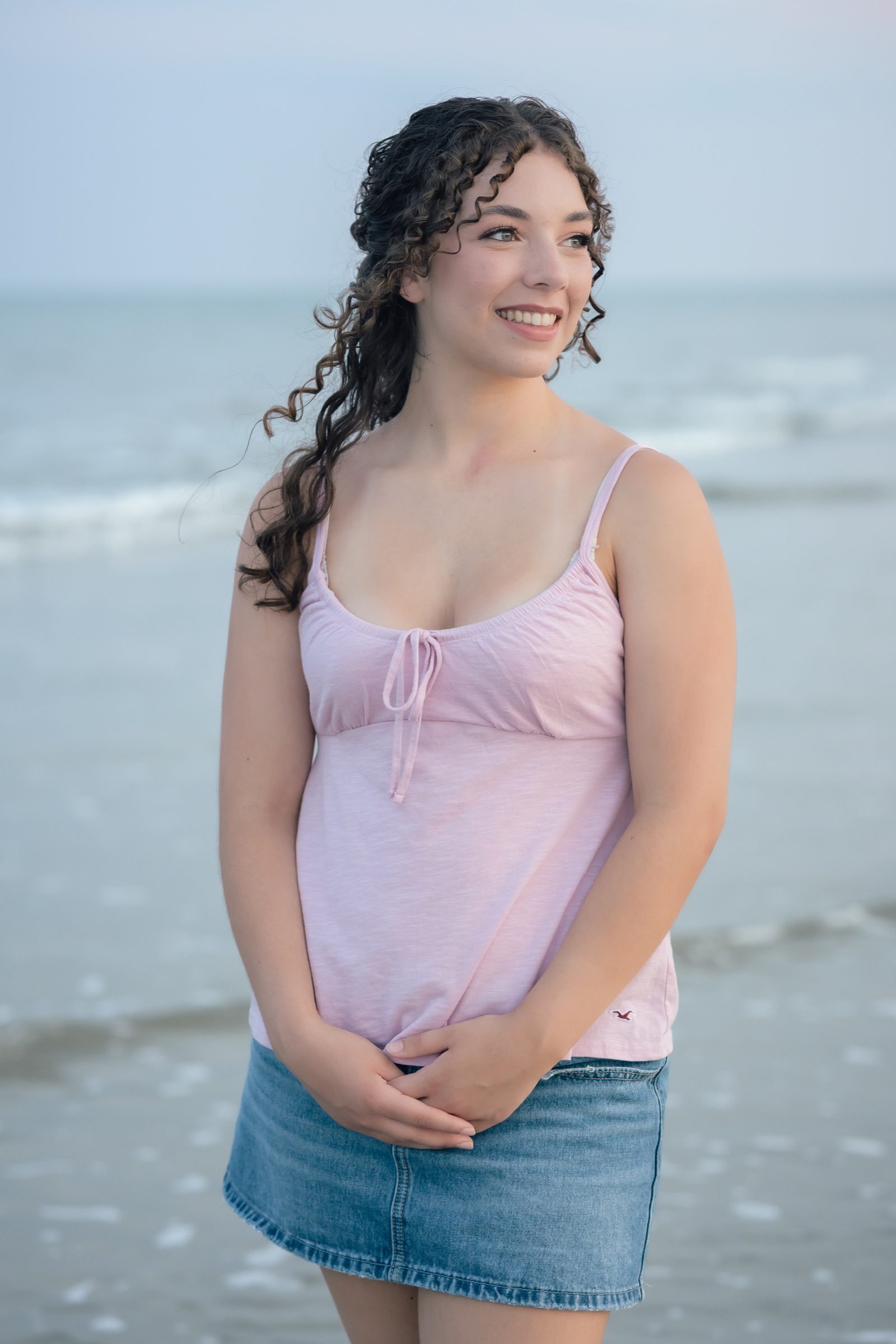 Senior smiling beside the ocean in a pink top