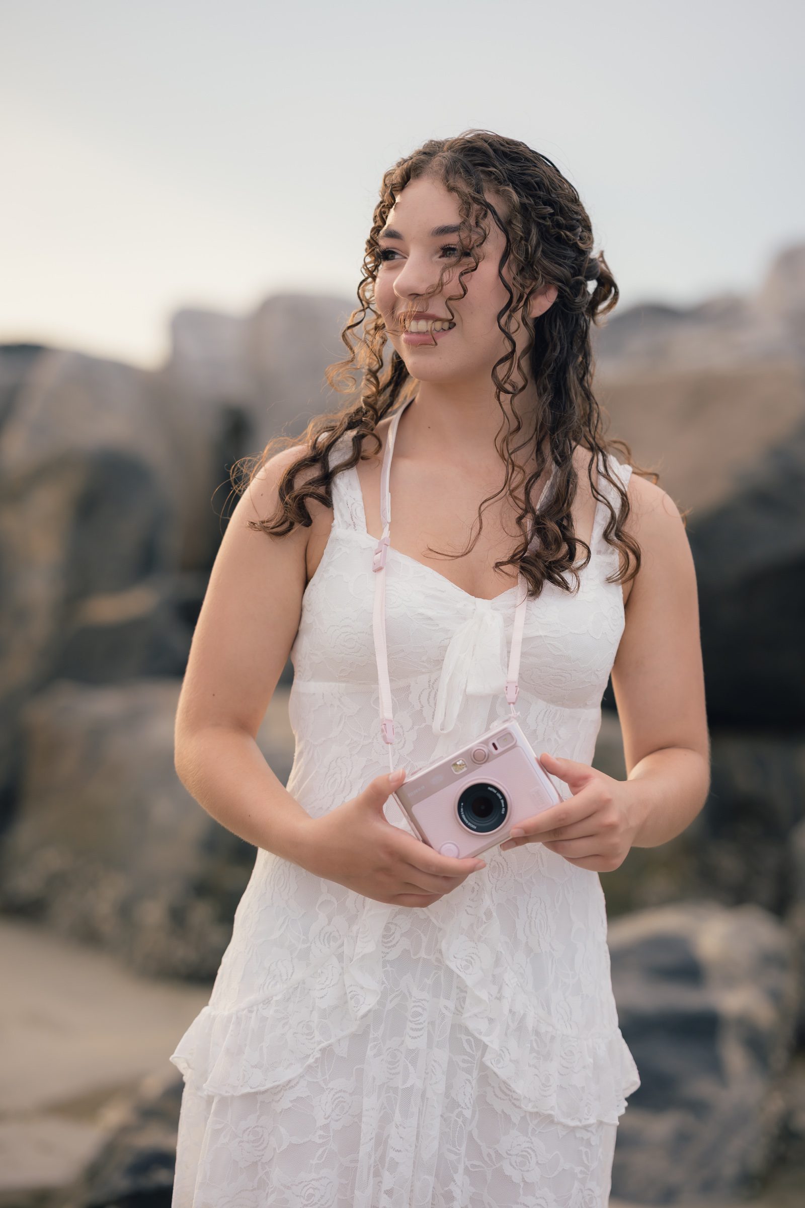 Senior laughing while holding a pink instant camera