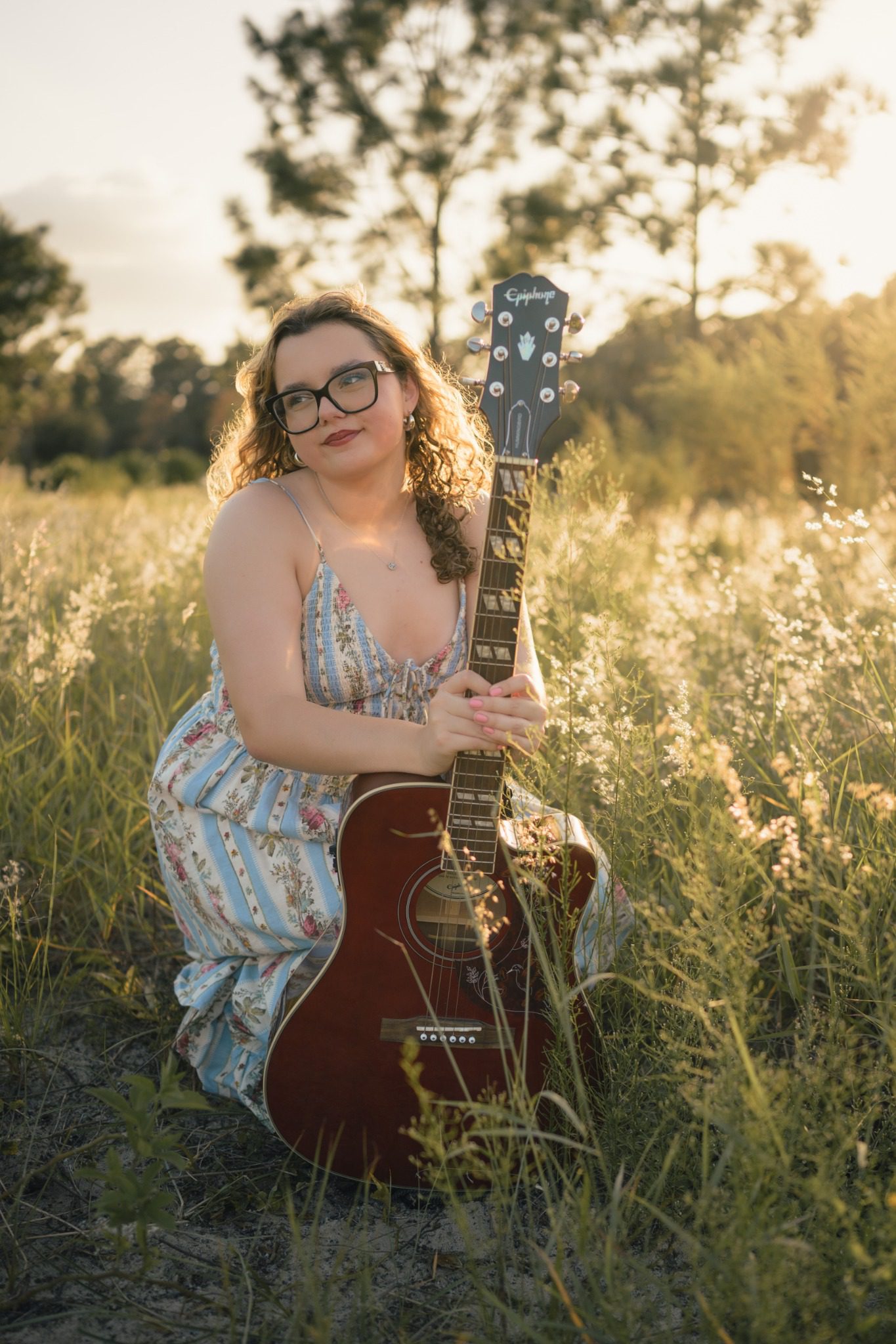 Senior kneeling with an acoustic guitar during senior pictures near Orlando