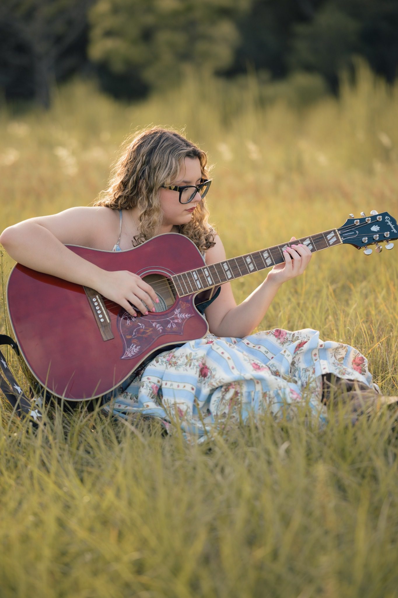 Senior playing an acoustic guitar in a sunlit Clermont field