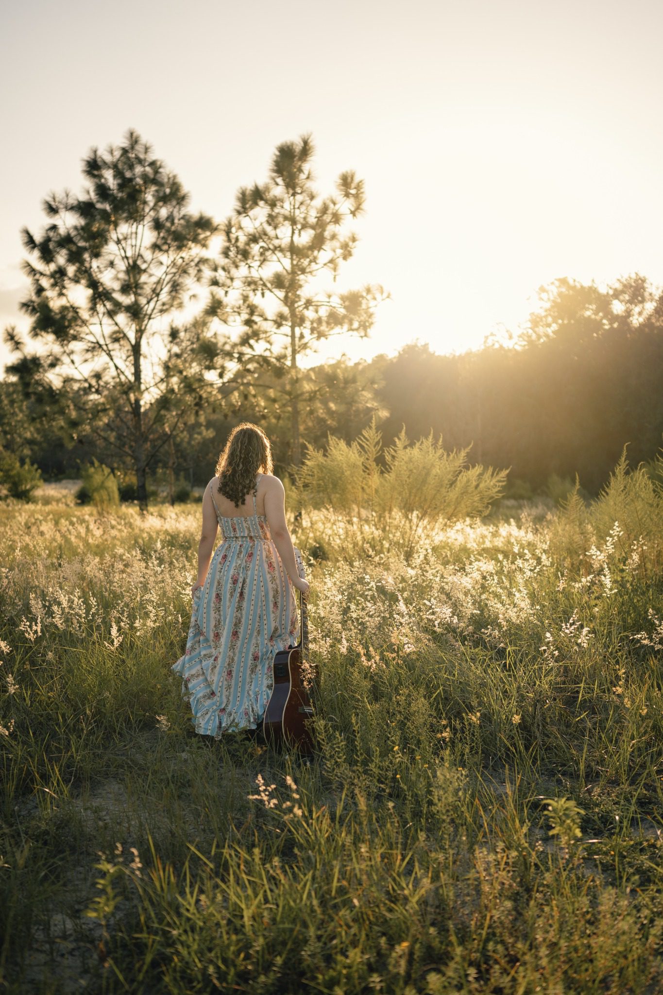Senior walking through a Lake Louisa field with an acoustic guitar
