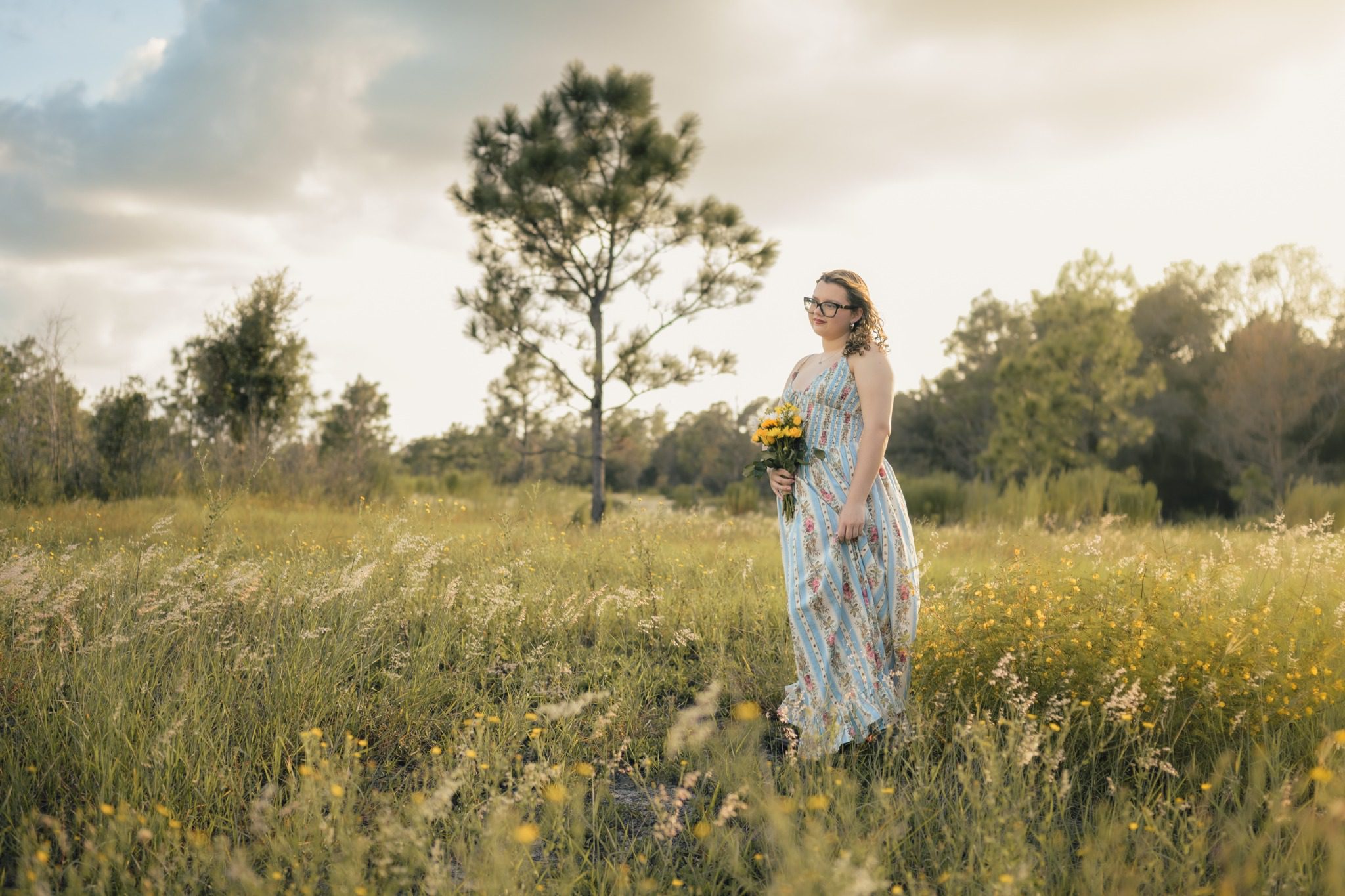 Senior in a floral dress standing in a wide field at Lake Louisa State Park in Clermont