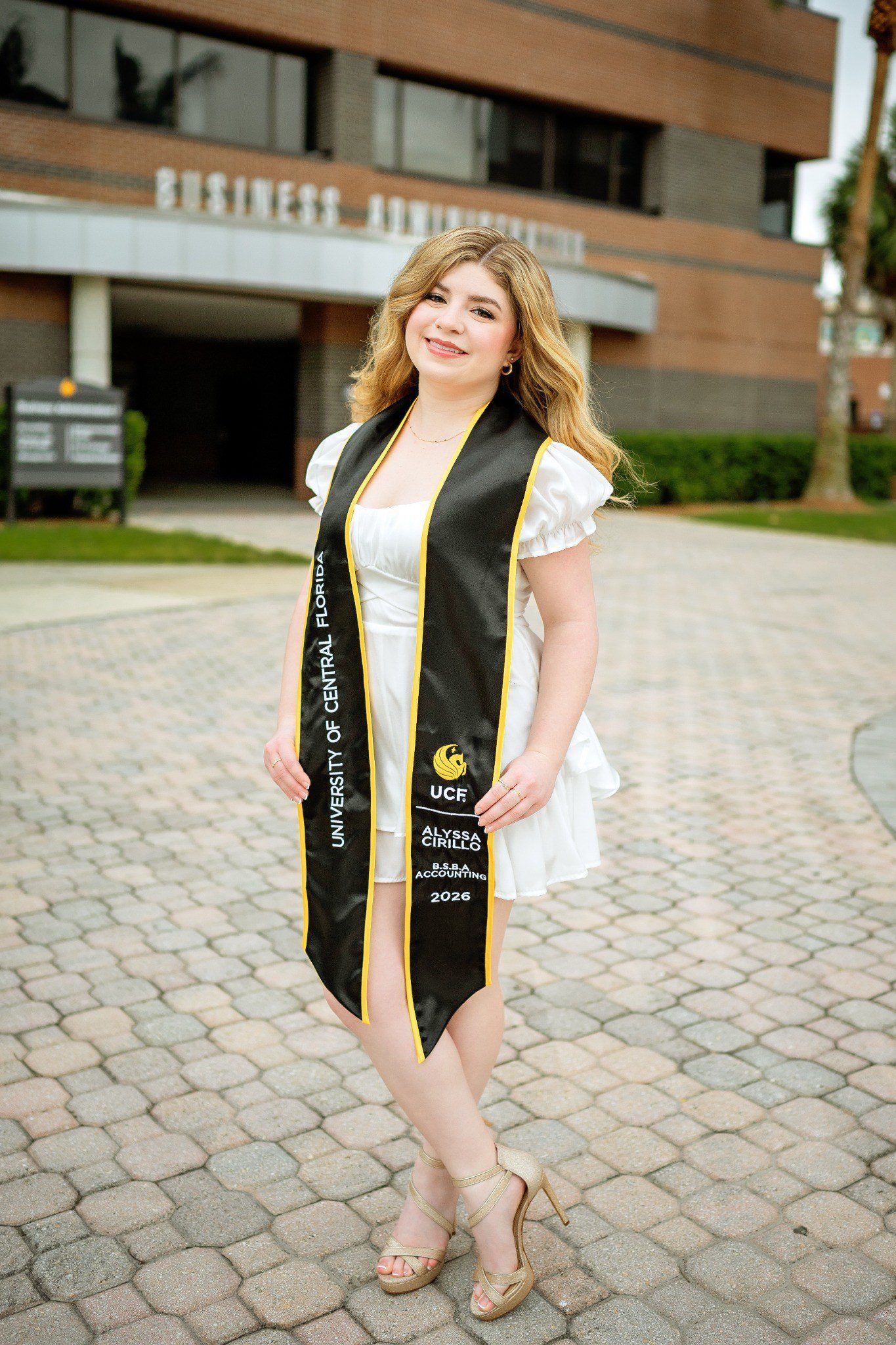 Accounting graduate wearing a personalized UCF stole outside the Business Administration building.