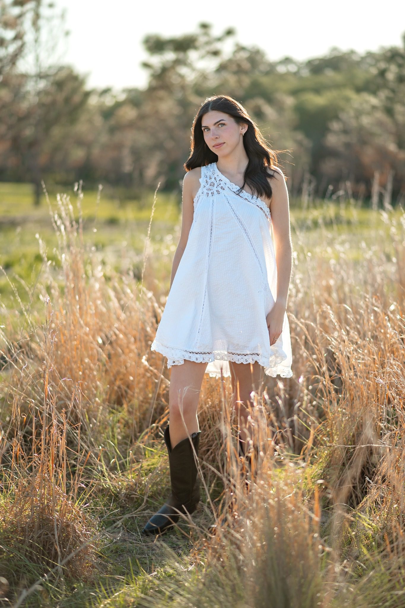 Senior standing in tall grass in a white dress and black boots in Clermont