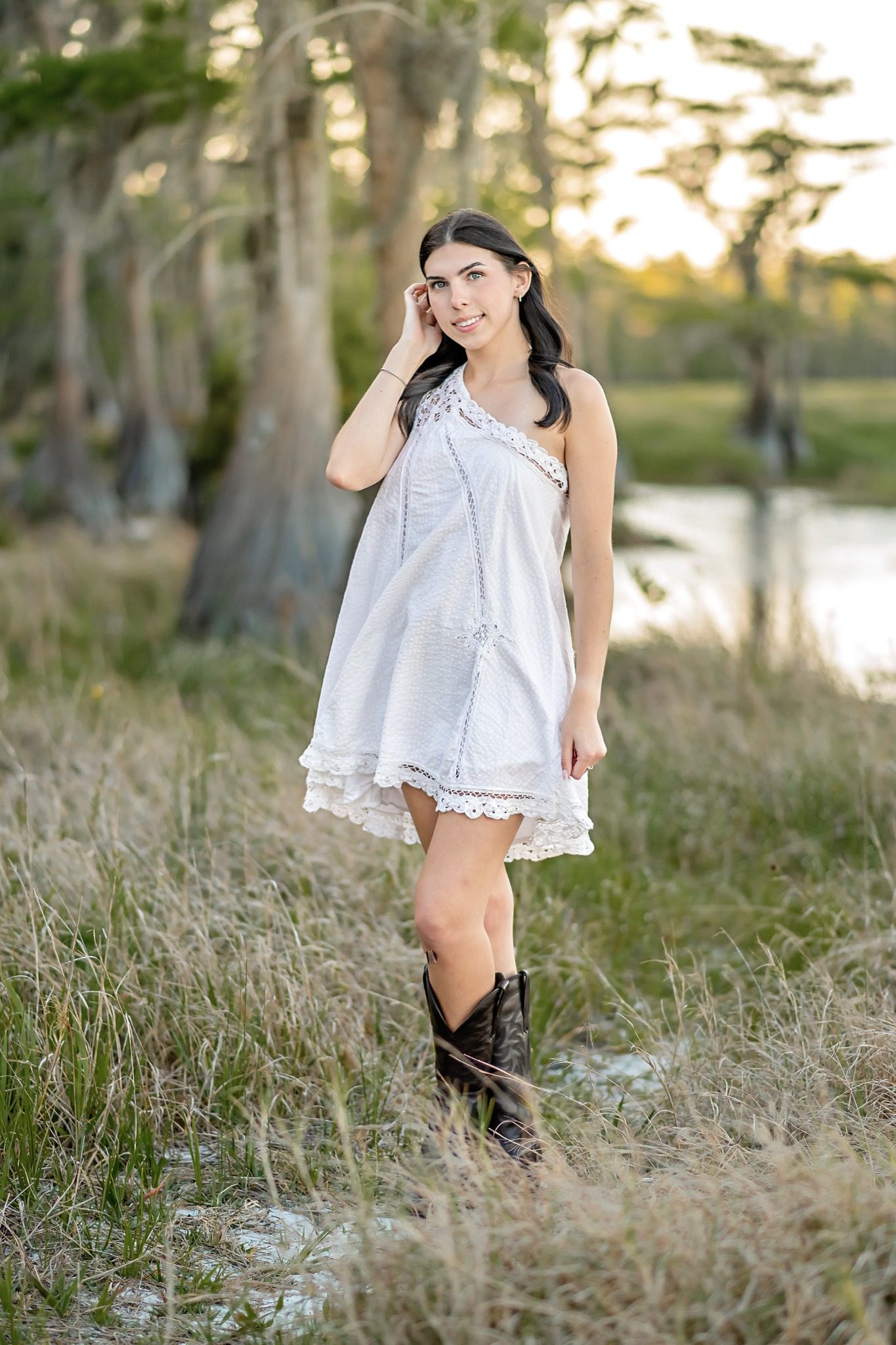 Senior portrait in a white dress along the grassy Lake Louisa shoreline