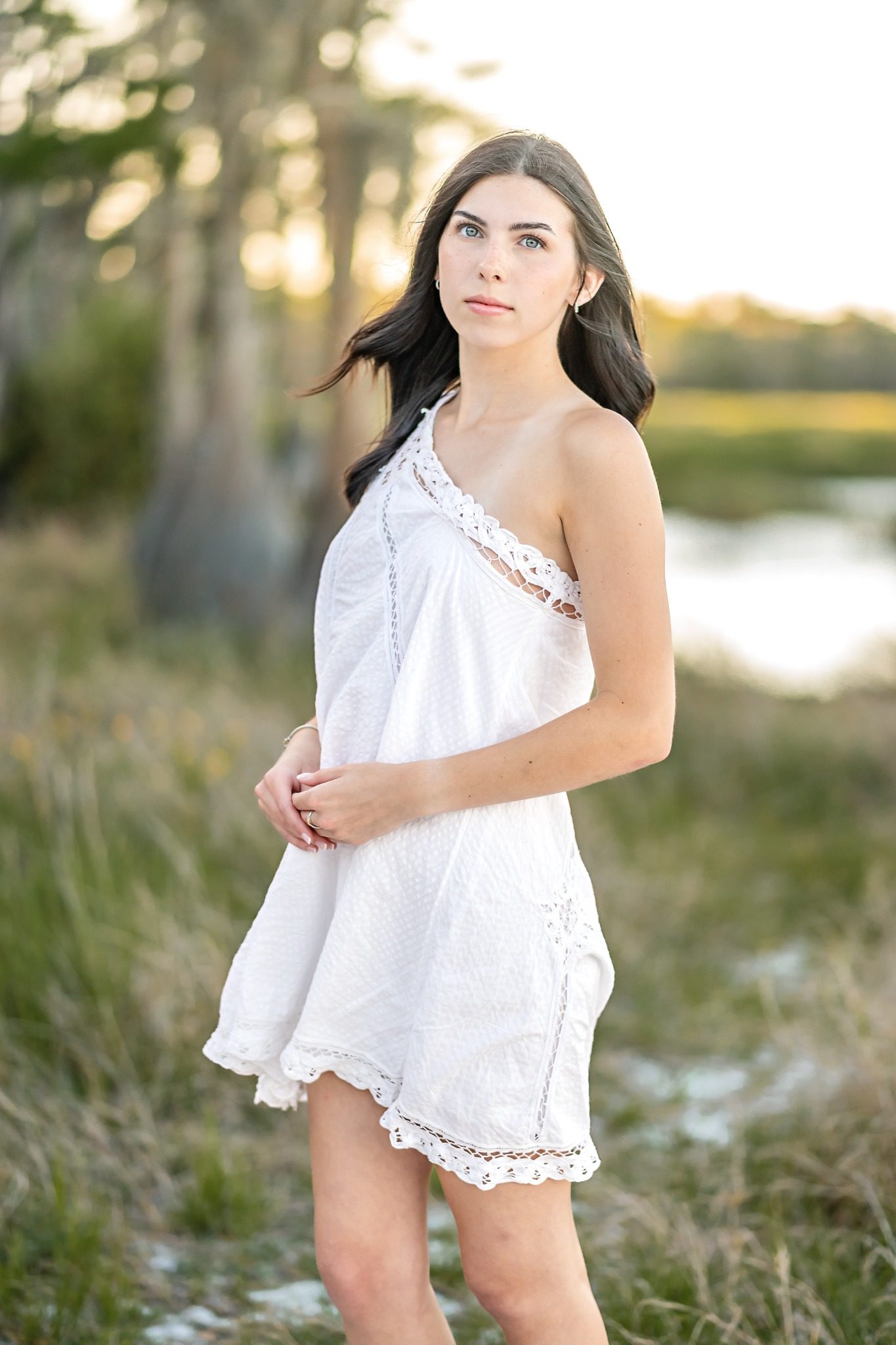 Close-up senior portrait beside Lake Louisa in a white dress