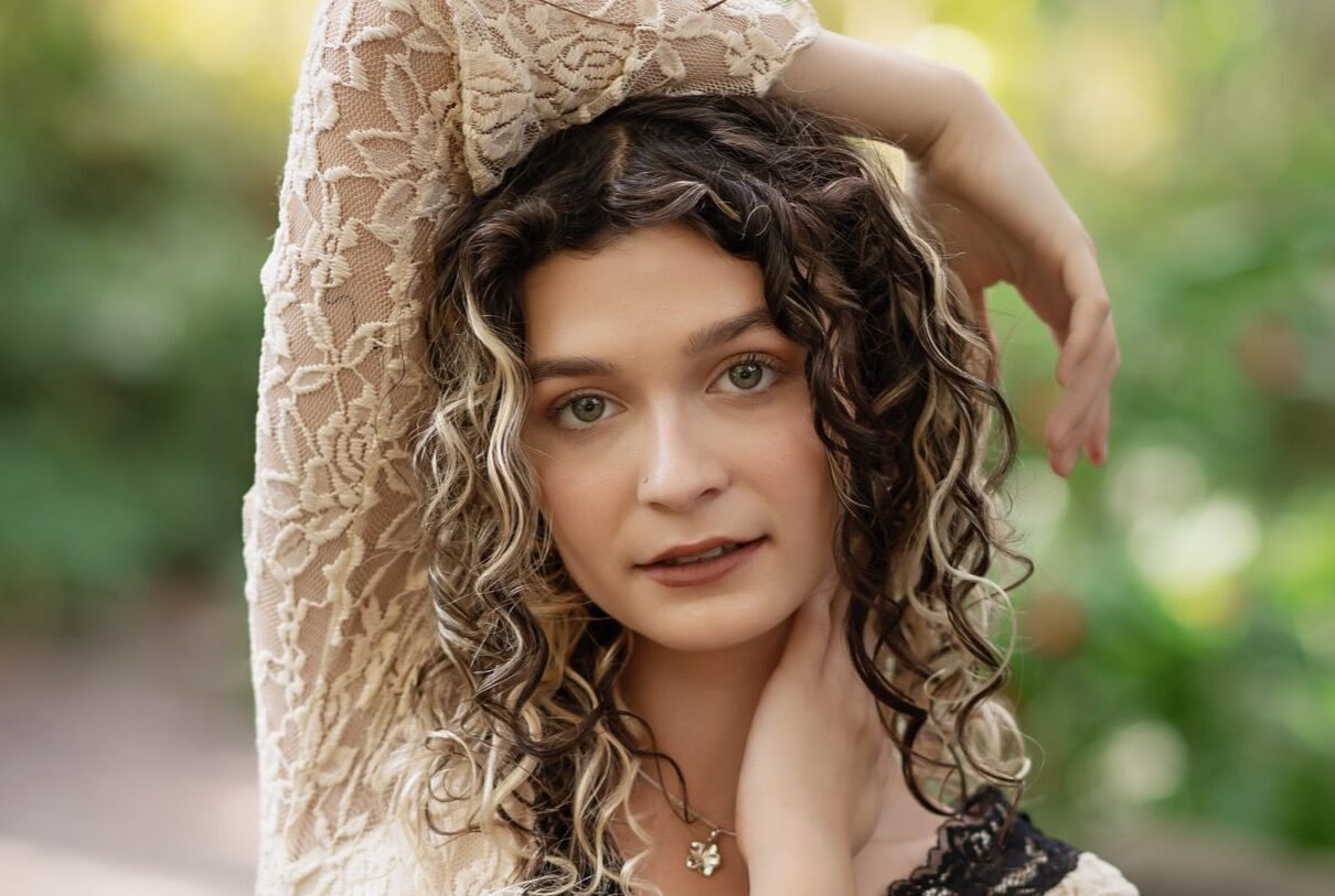 Close-up senior portrait in a cream lace dress with sunlit greenery at Dickson Azalea Park